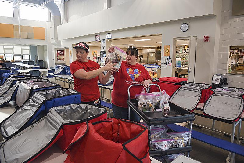 Stacy Smith and Marie Leppo Turner fill the coolers with food. This photo was taken before the governor mandated social distancing and masks.