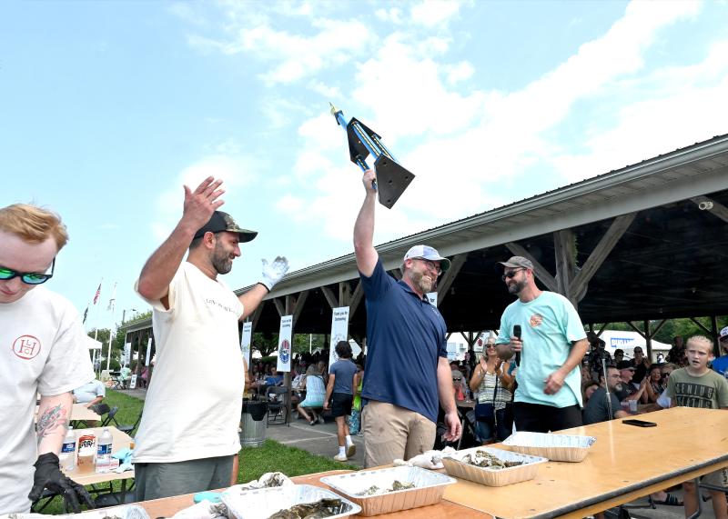 Dan Worrell, aka “Dan the Oyster Man, with the Fallen Pine Oyster Company of Girdletree, Md., is the Delaware Seafood Festival oyster-shucking champion. On stage are (l-r) Johnie McKay of Lewes Oyster House, Sean Corea of the Lewes Oyster House, Worrell and Ryan Stevenson, event coordinator for the Delaware Seafood Festival. TED PFIRRMANN PHOTOS