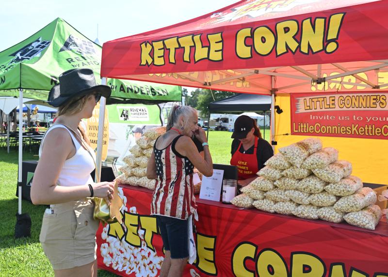 Hannah Schock, left, and Cindy Robinson visit Creama Jester and owner John Sweeney of Little Connie’s Kettle Corn.