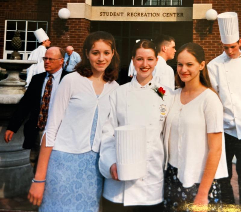 Paula Baker, center, holds her chef’s hat on graduation day at the Culinary Institute of America in New York in 2000. She started her career at a Philadelphia restaurant, before working in hotel kitchens in Plymouth Meeting, Pa., and Boston, Mass. She and her husband moved to Delaware in 2004. PHOTO COURTESY OF PAULA BAKER