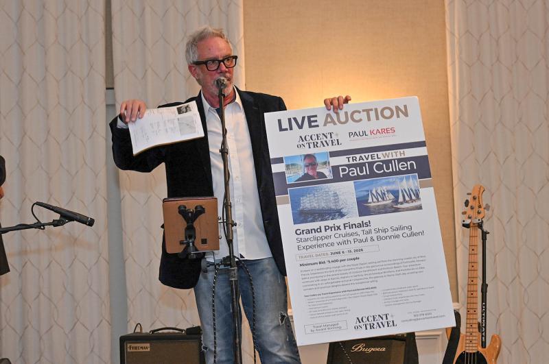 Paul Cullen holds a live auction item for a cruise on the tall ship Royal Clipper. The sailing experience from Nice, France takes guests to the Grand Prix finals in Fontvieille, Monaco.